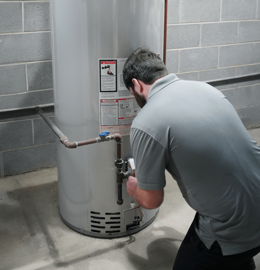 A Tyler Heating & Cooling employee servicing a water heater