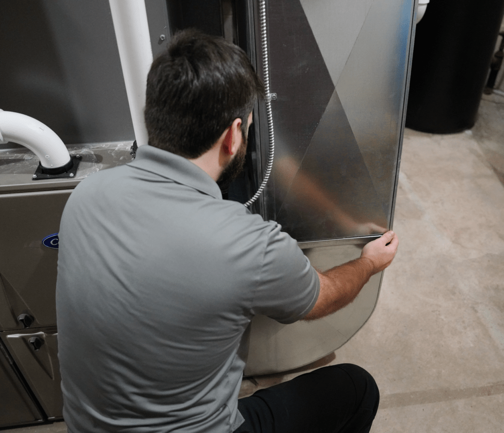 A Tyler Heating & Cooling employee inspecting the ductwork of a small business